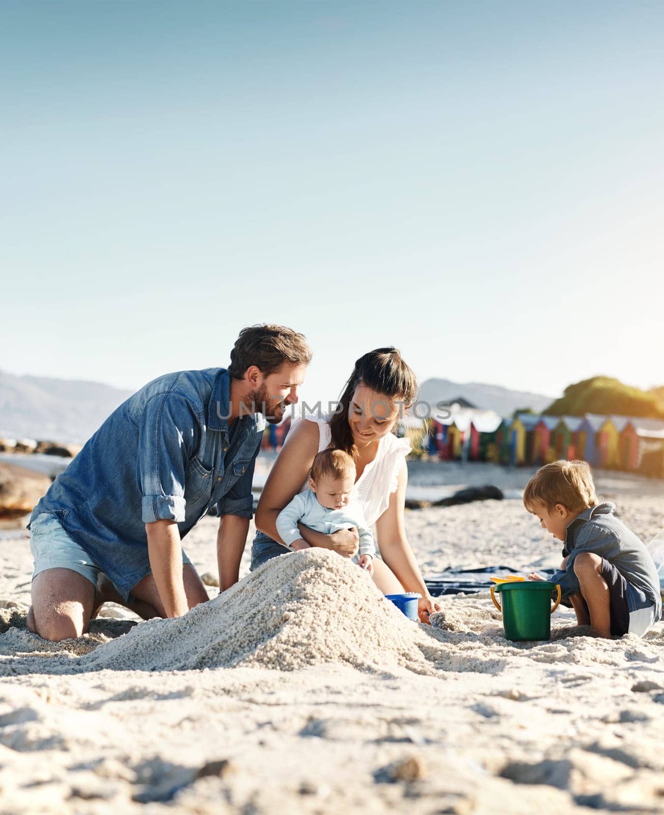 Sandcastle, holiday and children at the beach with family, love and support. Baby, mom and dad together with kids playing in the sun with happiness and smile by the ocean and mockup with bonding.