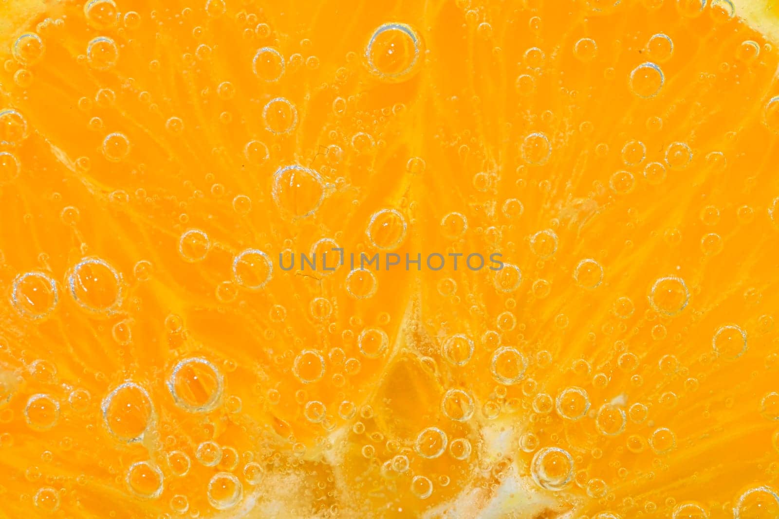 Slice of orange fruit in sparkling water. Orange fruit slice covered by bubbles in carbonated water. Orange fruit slice in water with bubbles. Close-up, macro horizontal image