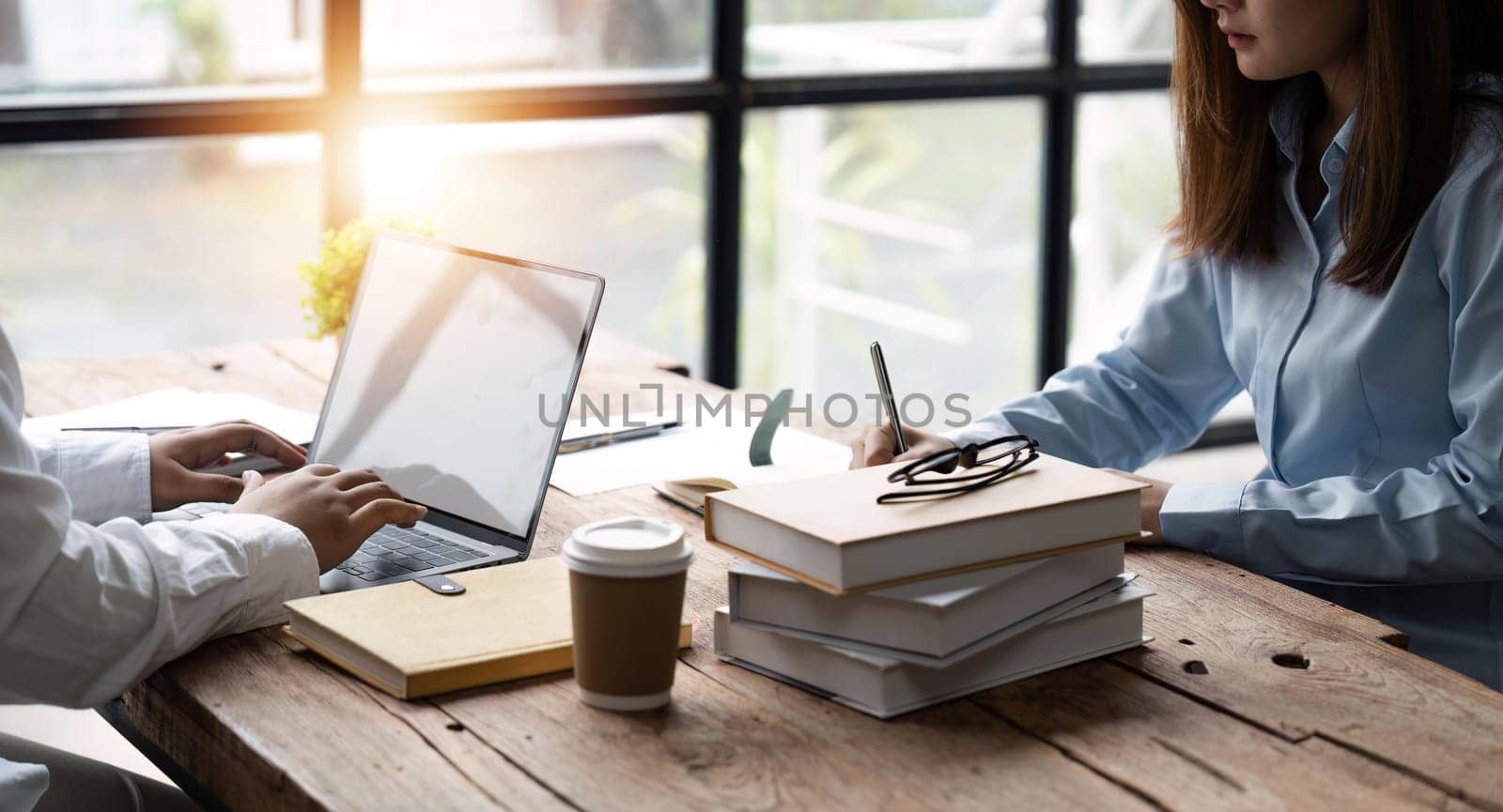 Distracted from preparing college project happy young laughing diverse classmates having fun, telling jokes, enjoying carefree pause time together, sitting at table in library.