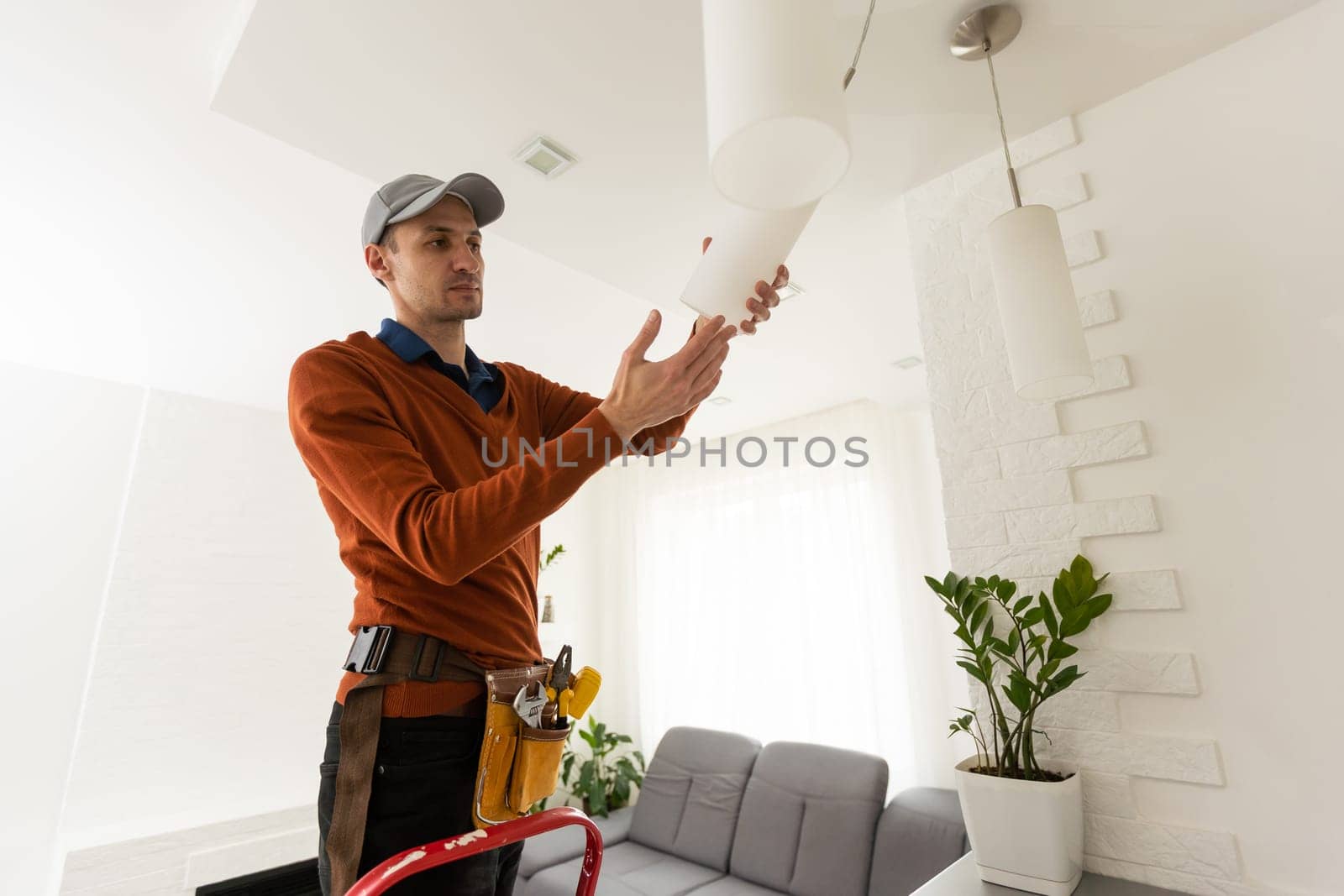 Electrician worker installation electric lamps light inside apartment. Construction decoration concept. by Andelov13