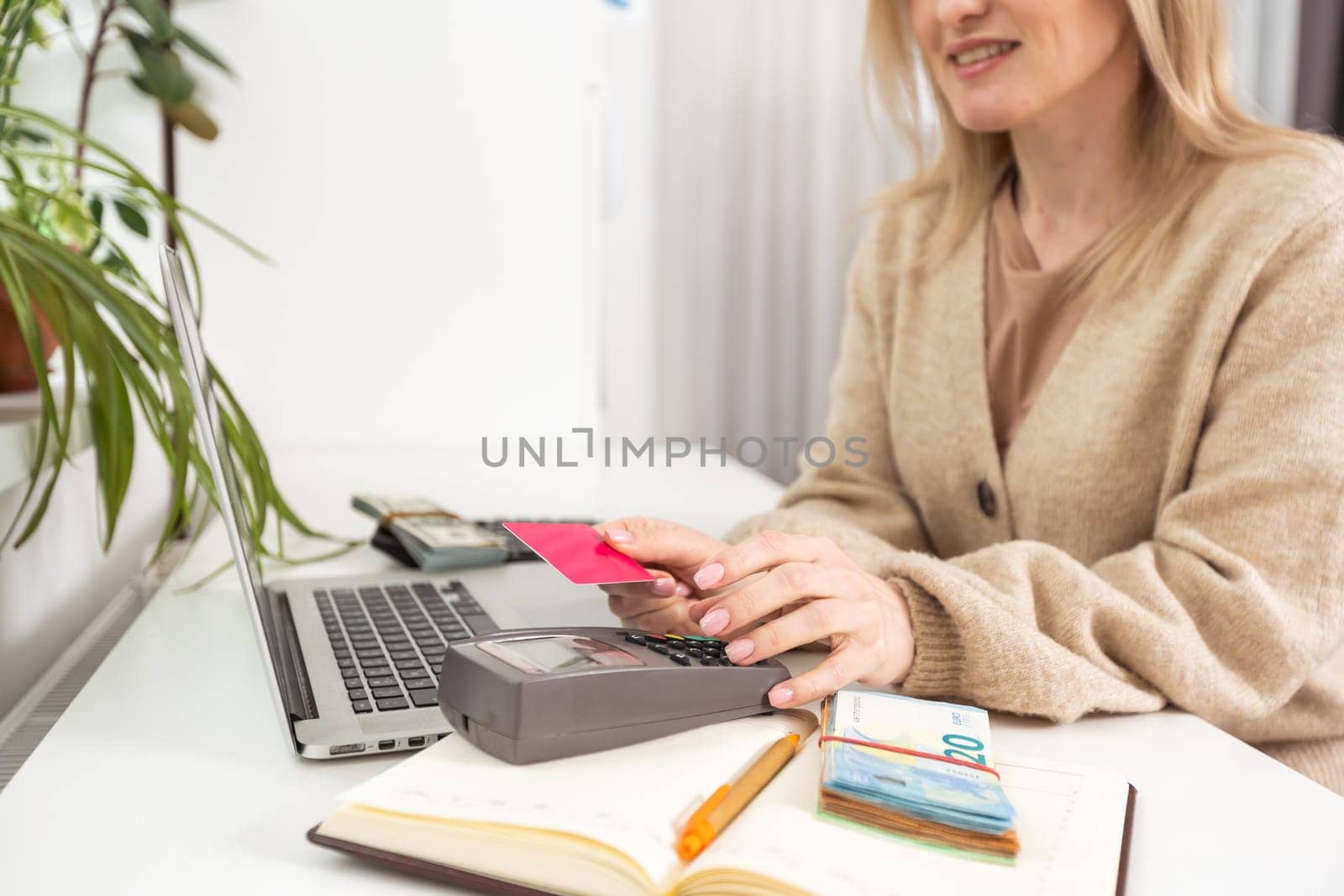 Woman with credit card using modern payment terminal on white background, closeup.