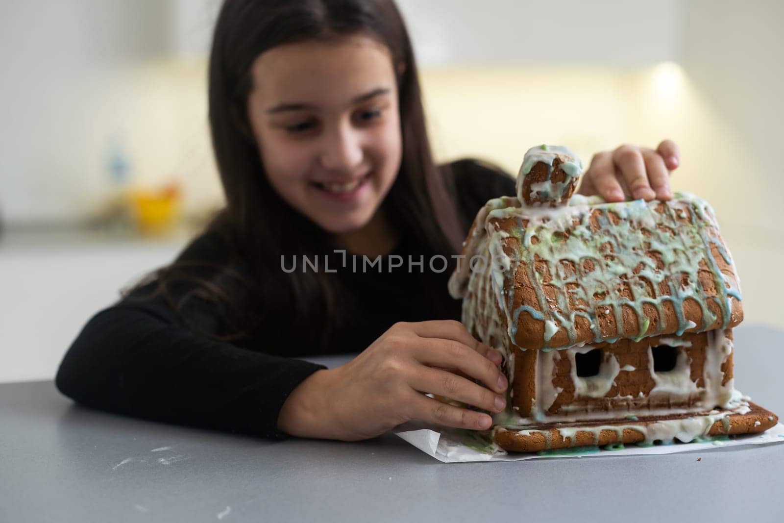 A teenage girl is eating a gingerbread house.