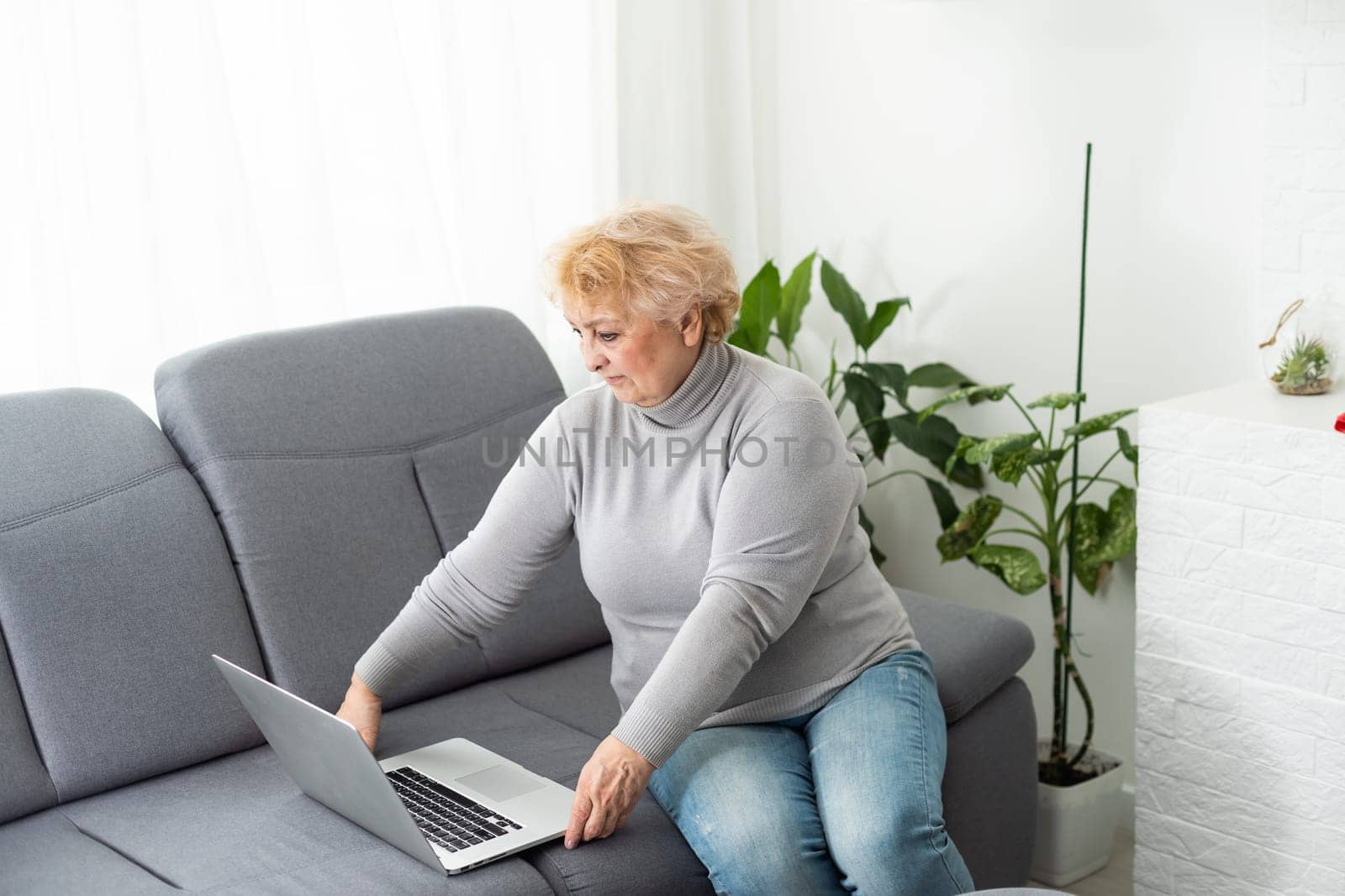 technology, old age and people concept - happy senior woman in glasses with laptop computer at home by Andelov13