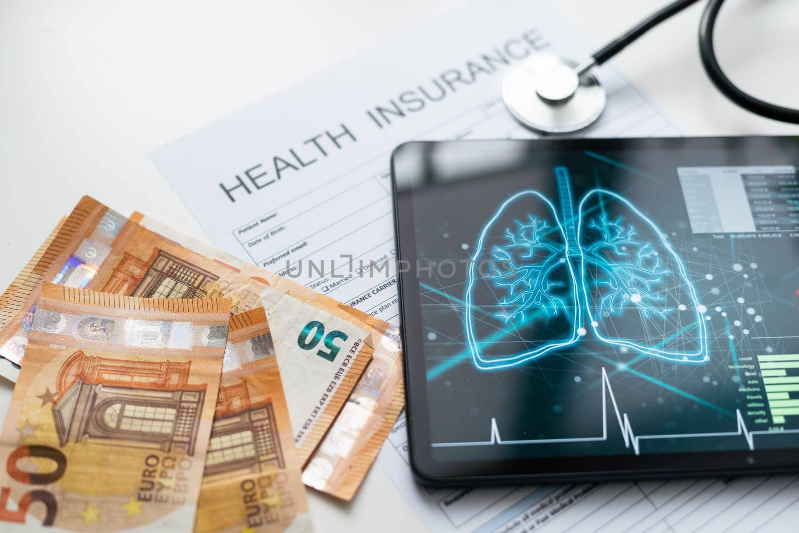 Modern social health insurance program. Tablet computer with healthcare application interface on screen. Stethoscope, x-ray image and cardiogram on wooden desk. Digital healthcare technologies.