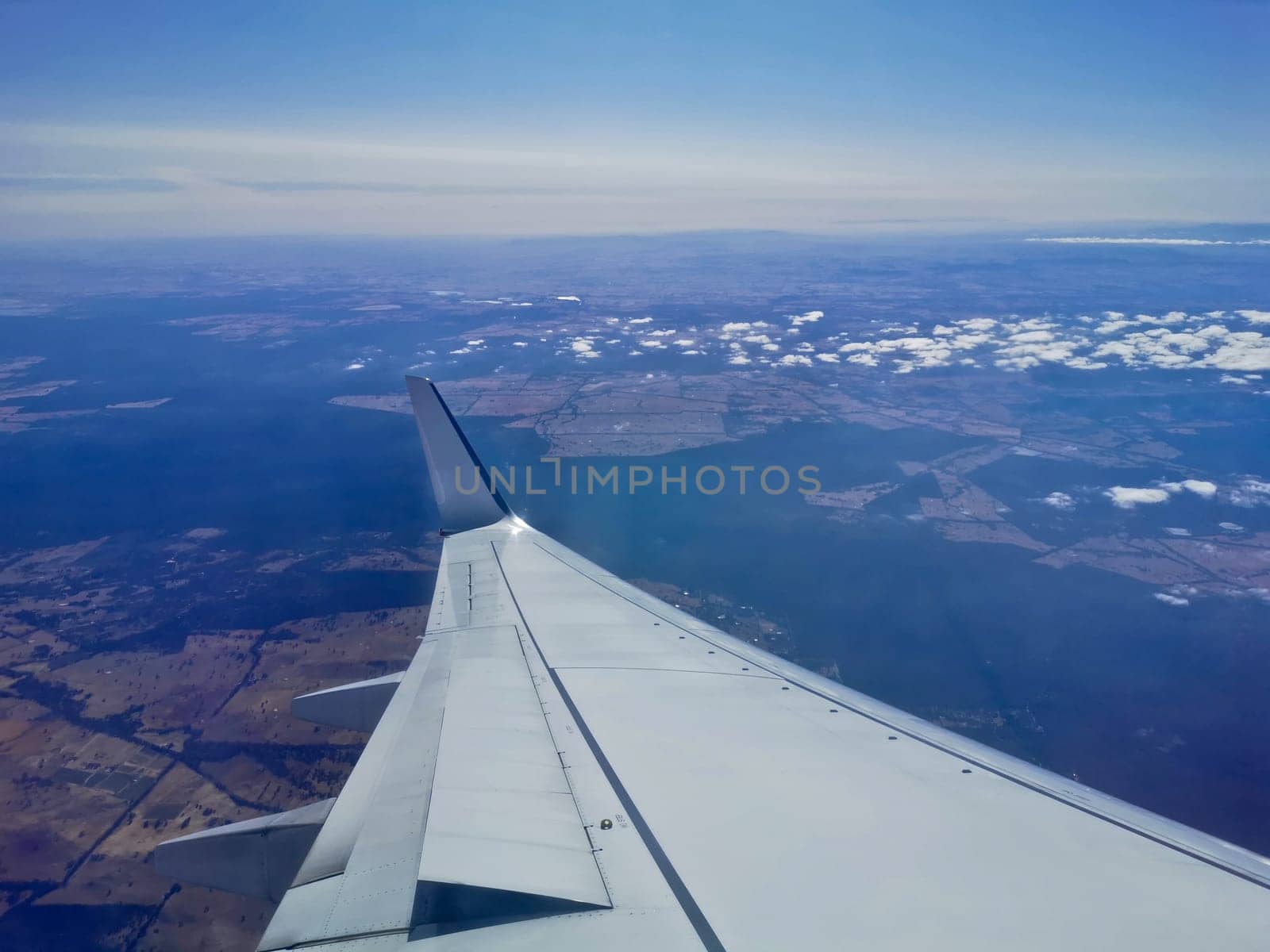 Aerial view scene from the left wingside of aeroplane flying in sunny day with blue sky