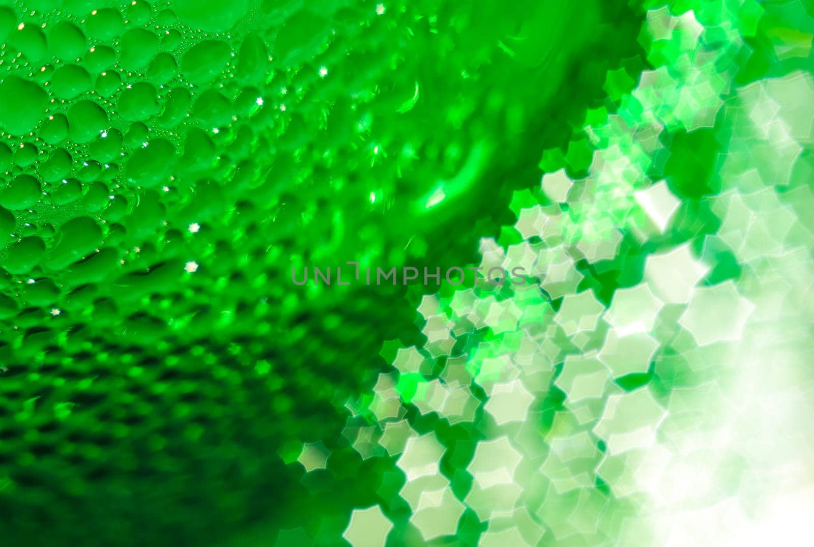 Green glass bottle, selective focus, beautiful blurred bokeh. Close-up. Drops of water on the glass passing in the bokeh in the form of a hexagonal star