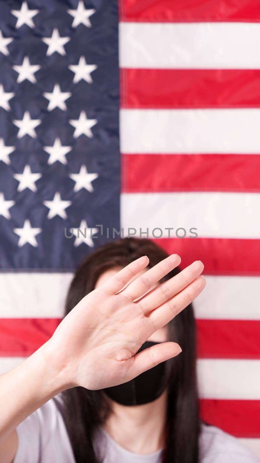 Unrecognized woman stretch out her palm to camera says stop abortion American flag on background. Selective focus. Anti domestic violence, racism racial discrimination. Women rights, social problems