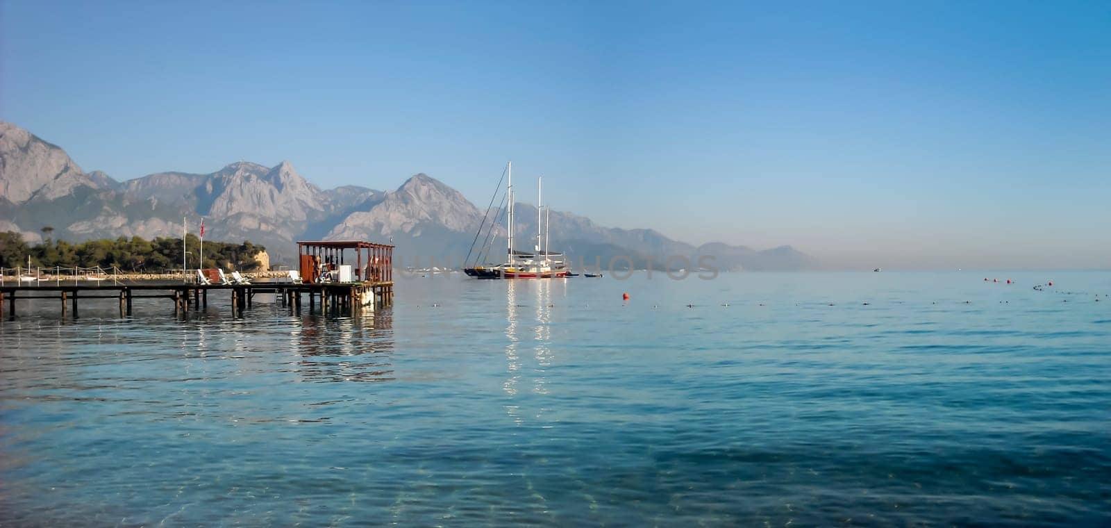 Kemer Antalia nice view of the sea. Beach Kemer Antalia with sand and mountains, the sea with the ship. Beautiful harbor near the sandy beach.