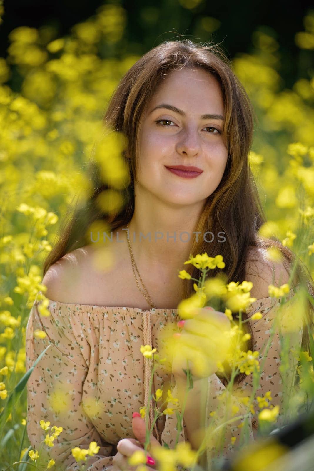 Portrait of a beautiful young woman surrounded by canola flowers.