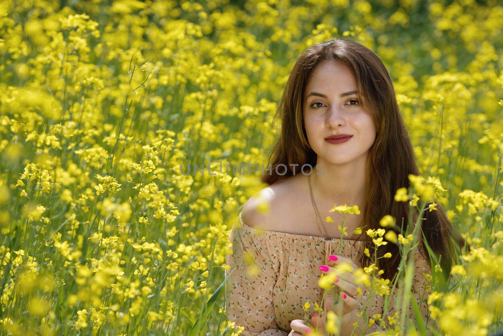 Portrait of a beautiful young woman surrounded by canola flowers.