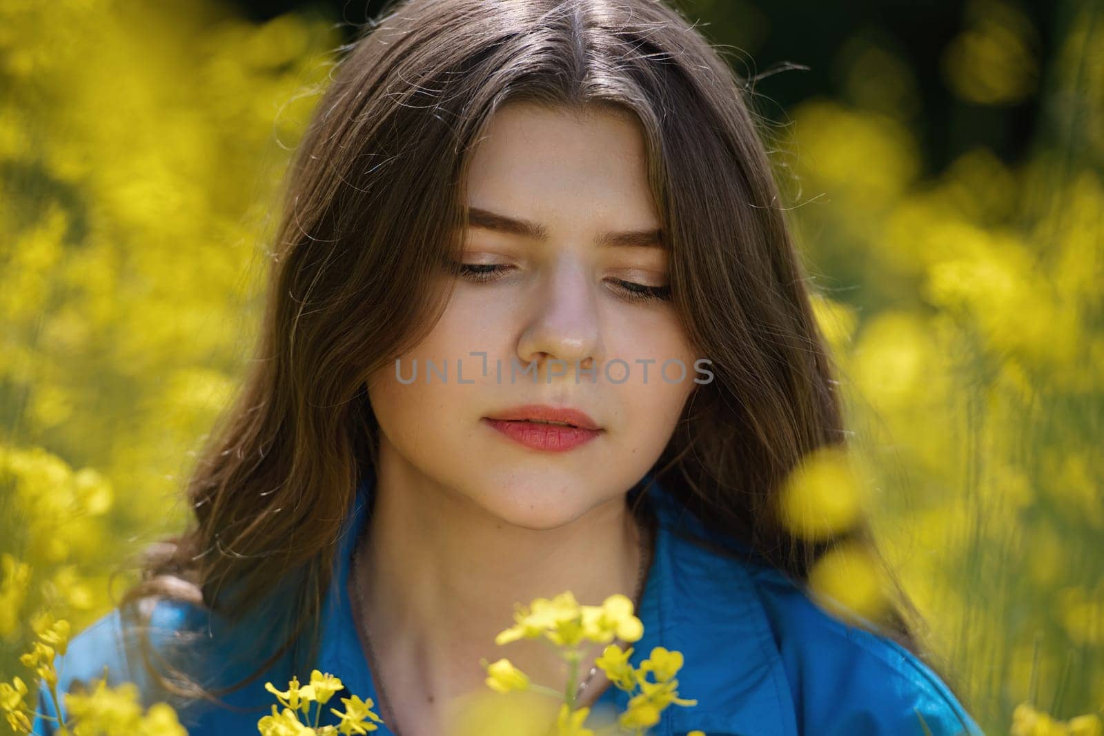 Portrait of a beautiful young woman surrounded by canola flowers.