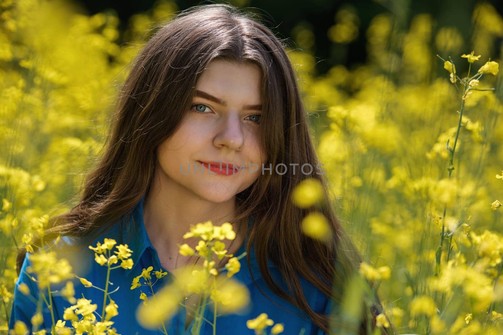 Portrait of a beautiful young woman surrounded by canola flowers. by leonik