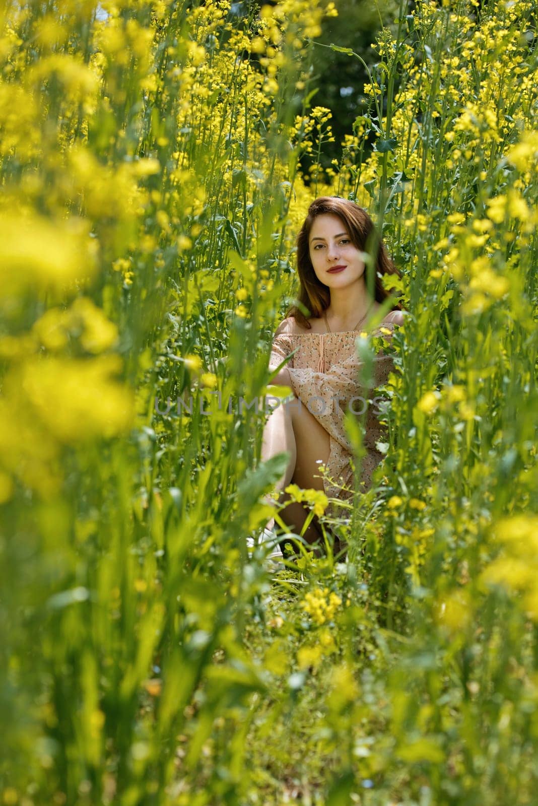 Young woman surrounded by canola flowers. Spring blossom field. by leonik