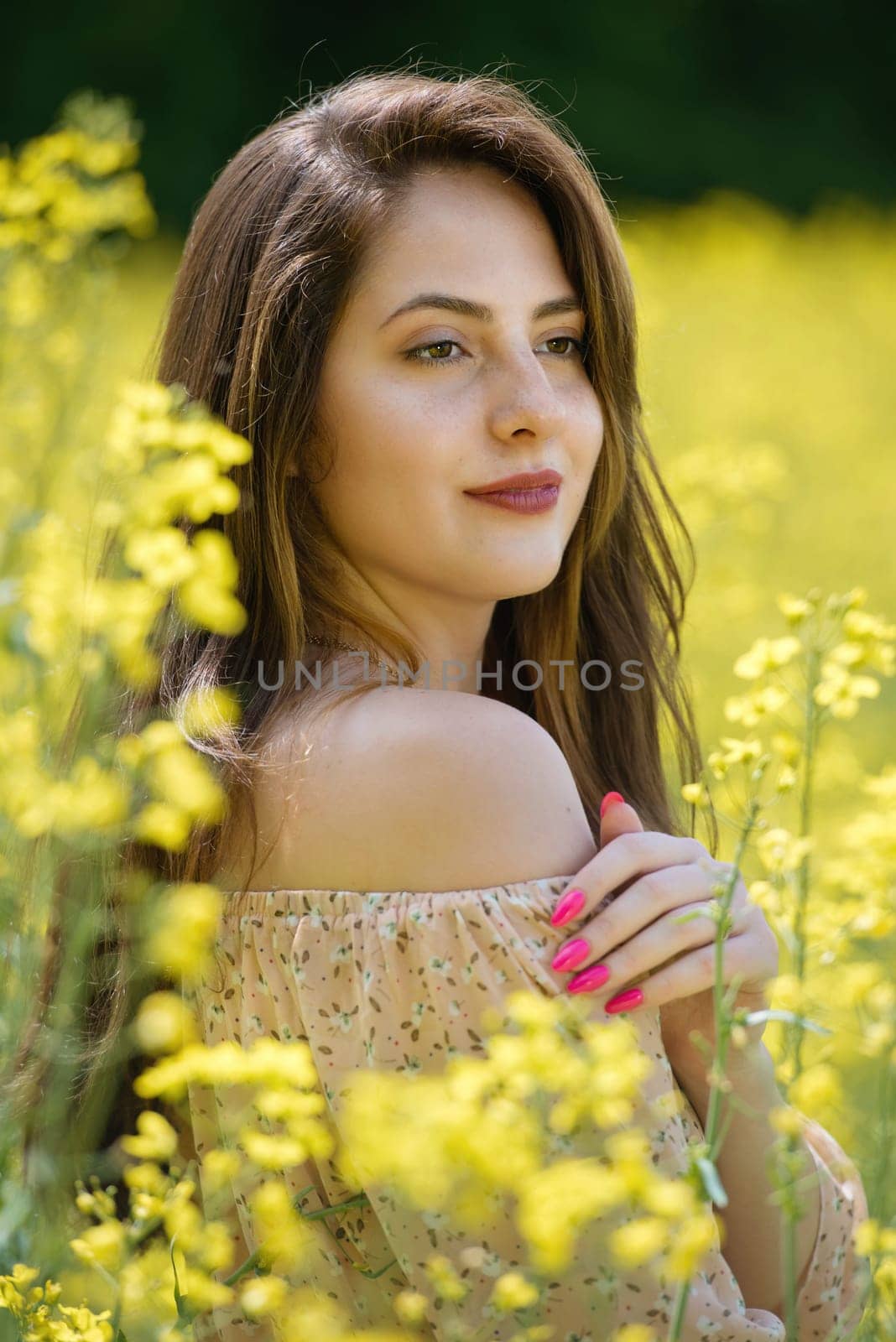Portrait of a beautiful young woman surrounded by canola flowers. by leonik