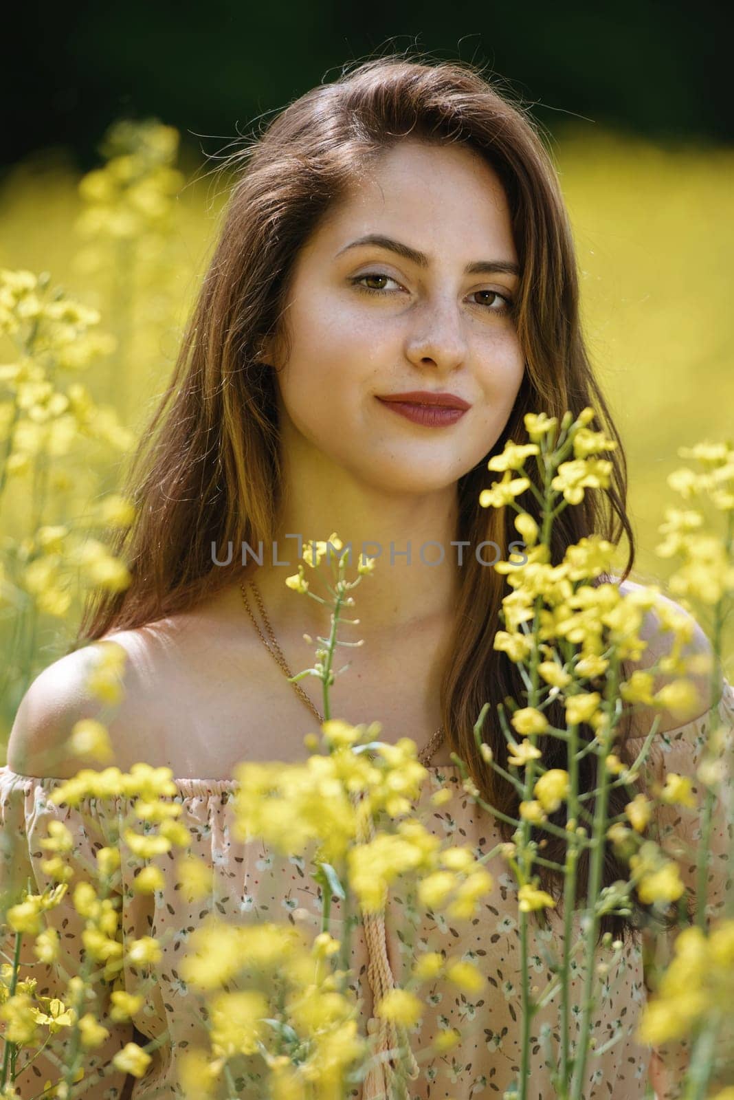 Portrait of a beautiful young woman surrounded by canola flowers. by leonik