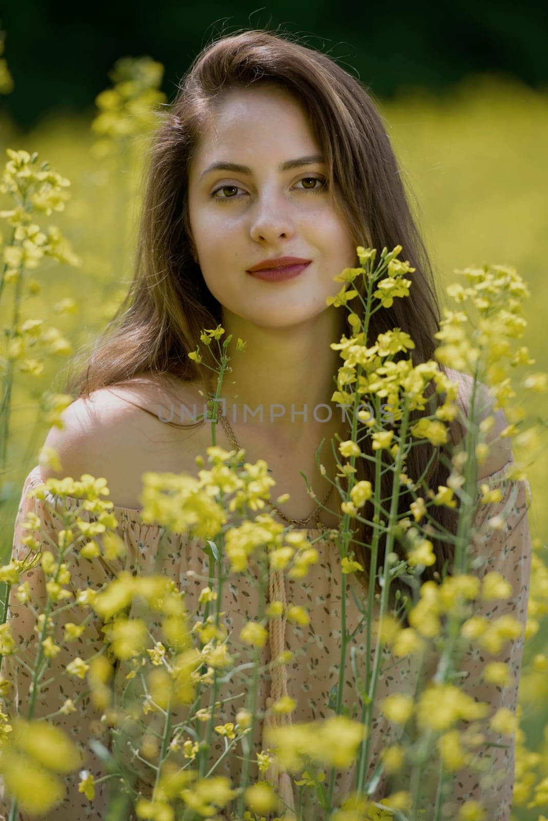 Portrait of a beautiful young woman surrounded by canola flowers.