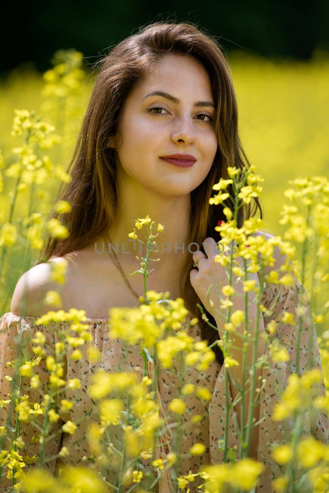 Portrait of a beautiful young woman surrounded by canola flowers.