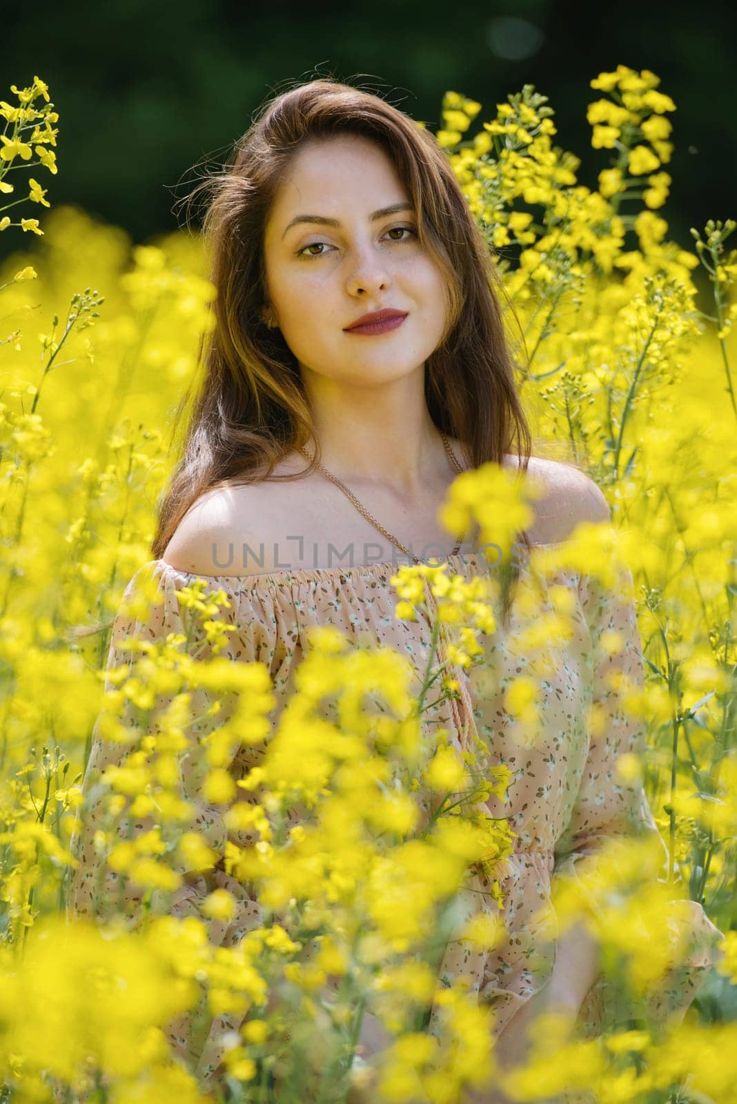 Portrait of a beautiful young woman surrounded by canola flowers.