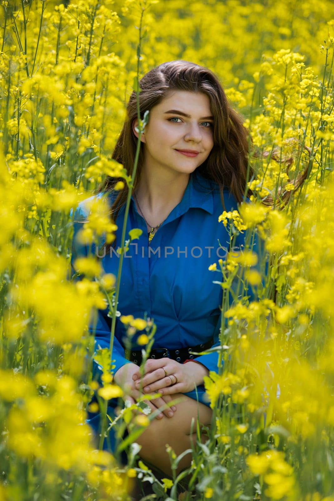 Portrait of a beautiful young woman surrounded by canola flowers.