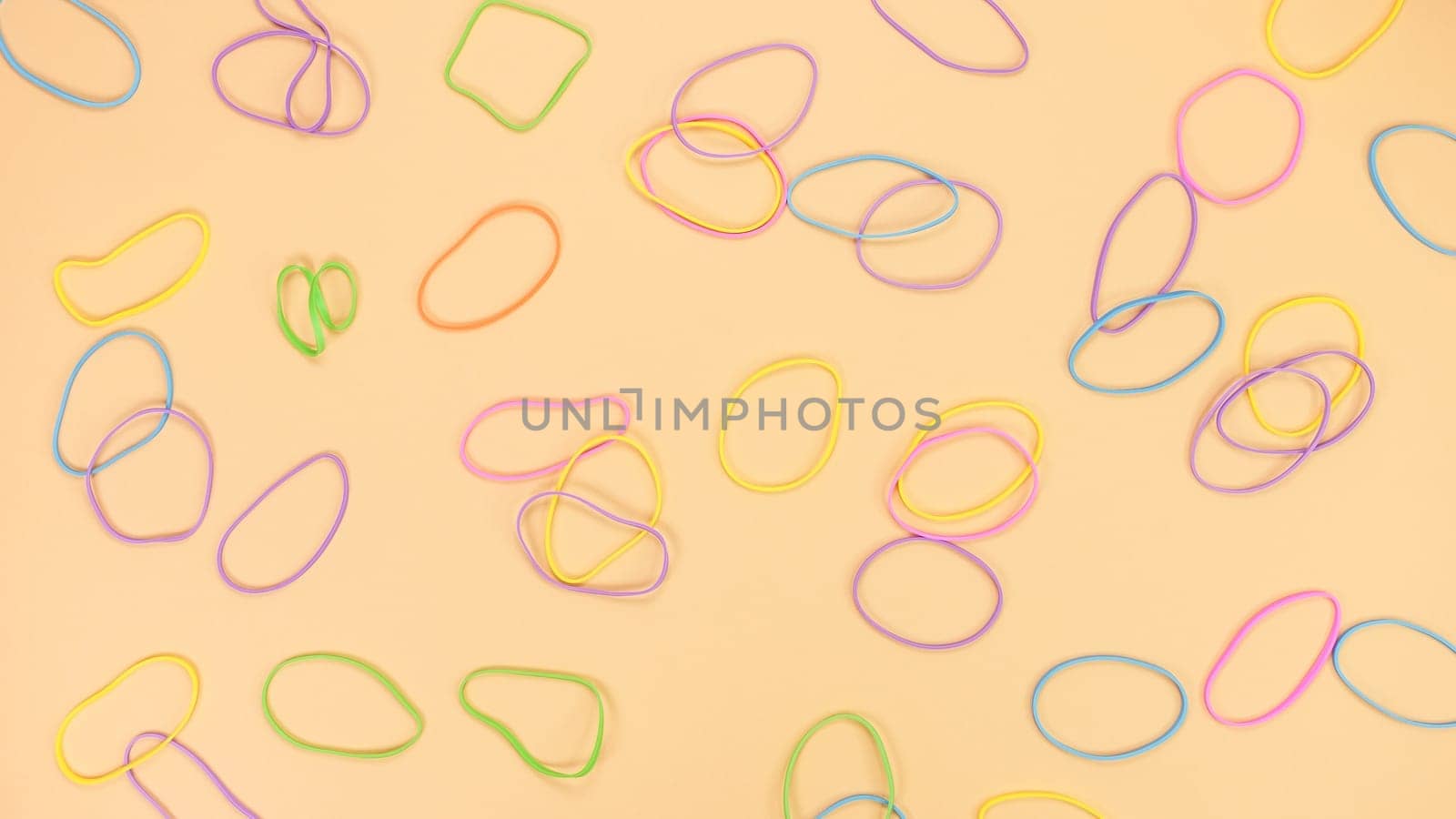 Colored rubber bands for money on bright yellow paper background. Abstract background. Stationery accessories. by JuliaDorian