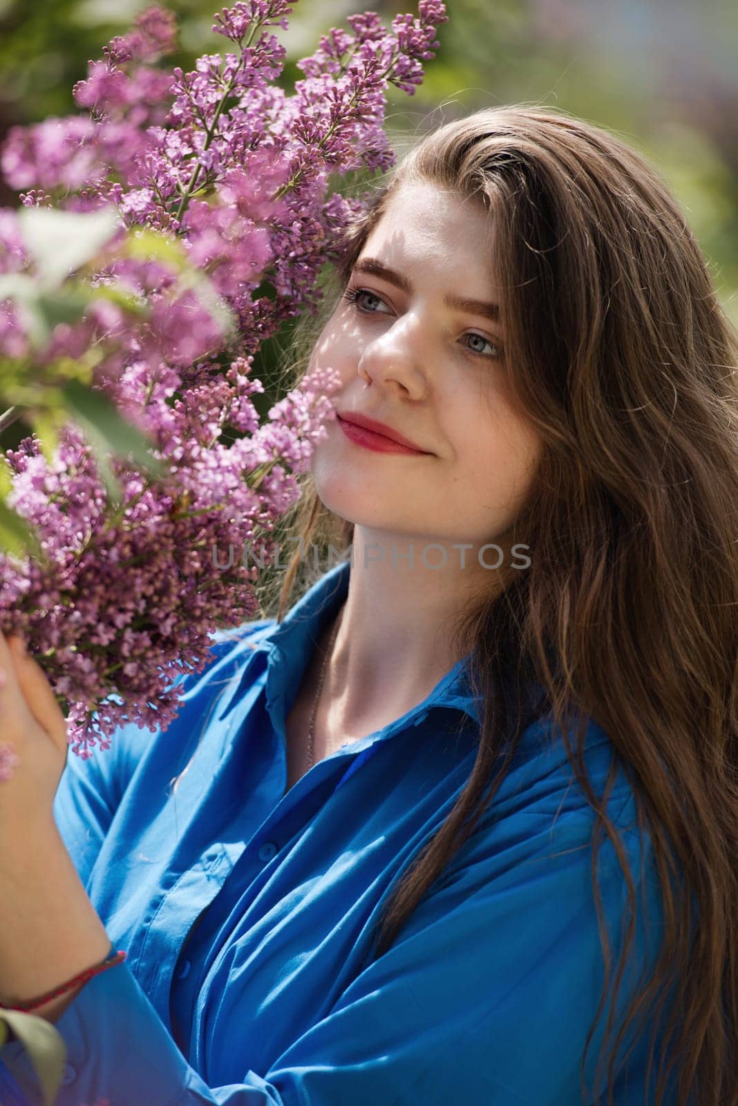 Portrait of a young woman in lilac flowers.