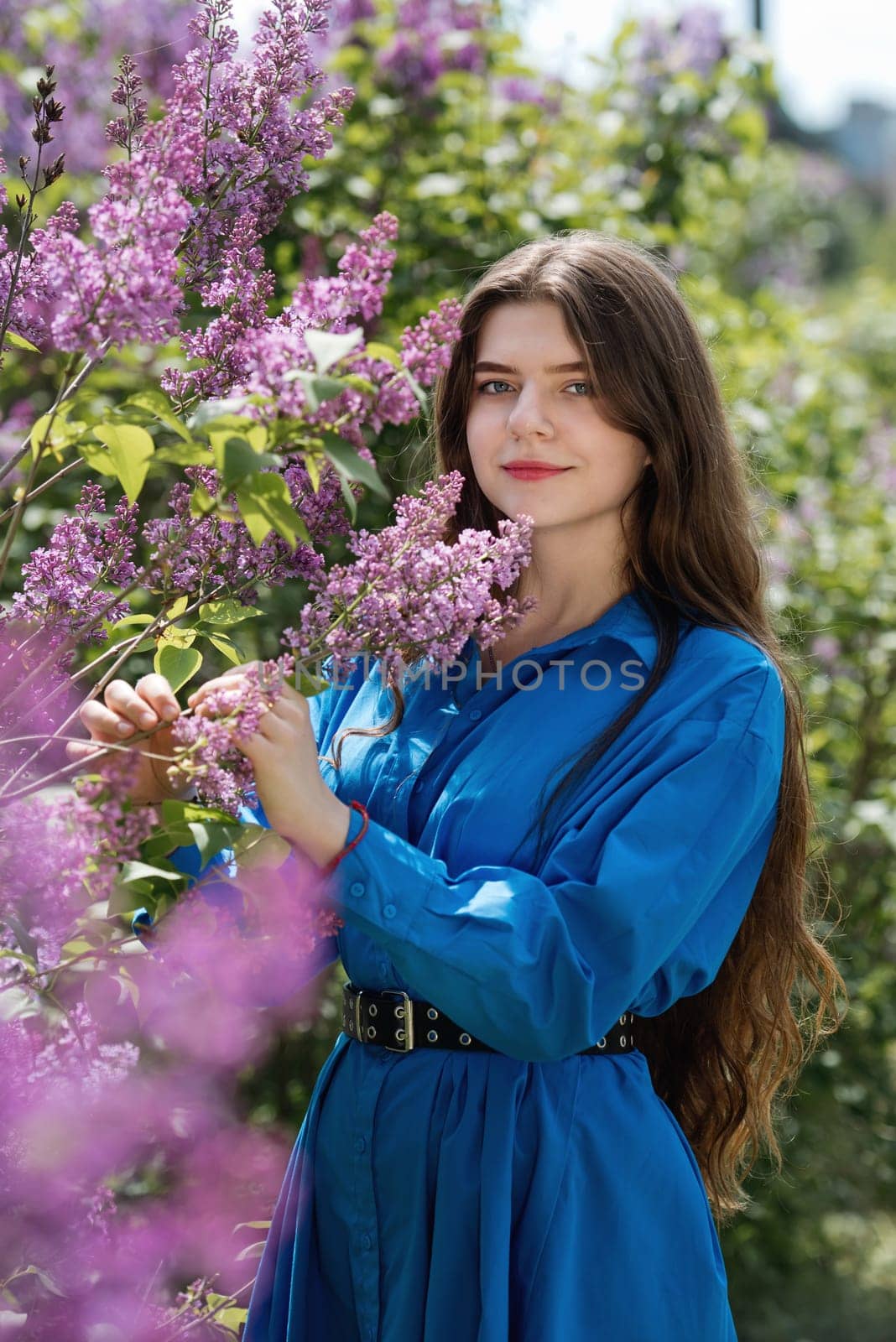 Portrait of a beautiful young woman surrounded by lilac flowers.