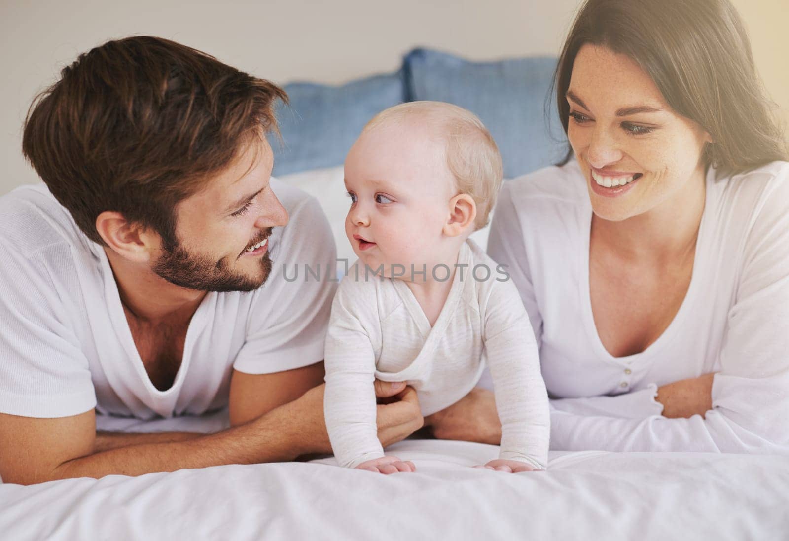 Happy family, mother and father with baby on bed for love, care and quality time together at home. Mom, dad and cute newborn child relaxing in bedroom for happiness, support and development of kids.
