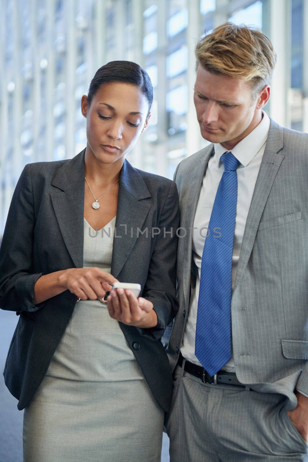 Using technology to further their business. two business colleagues standing and looking at something on a mobile phone