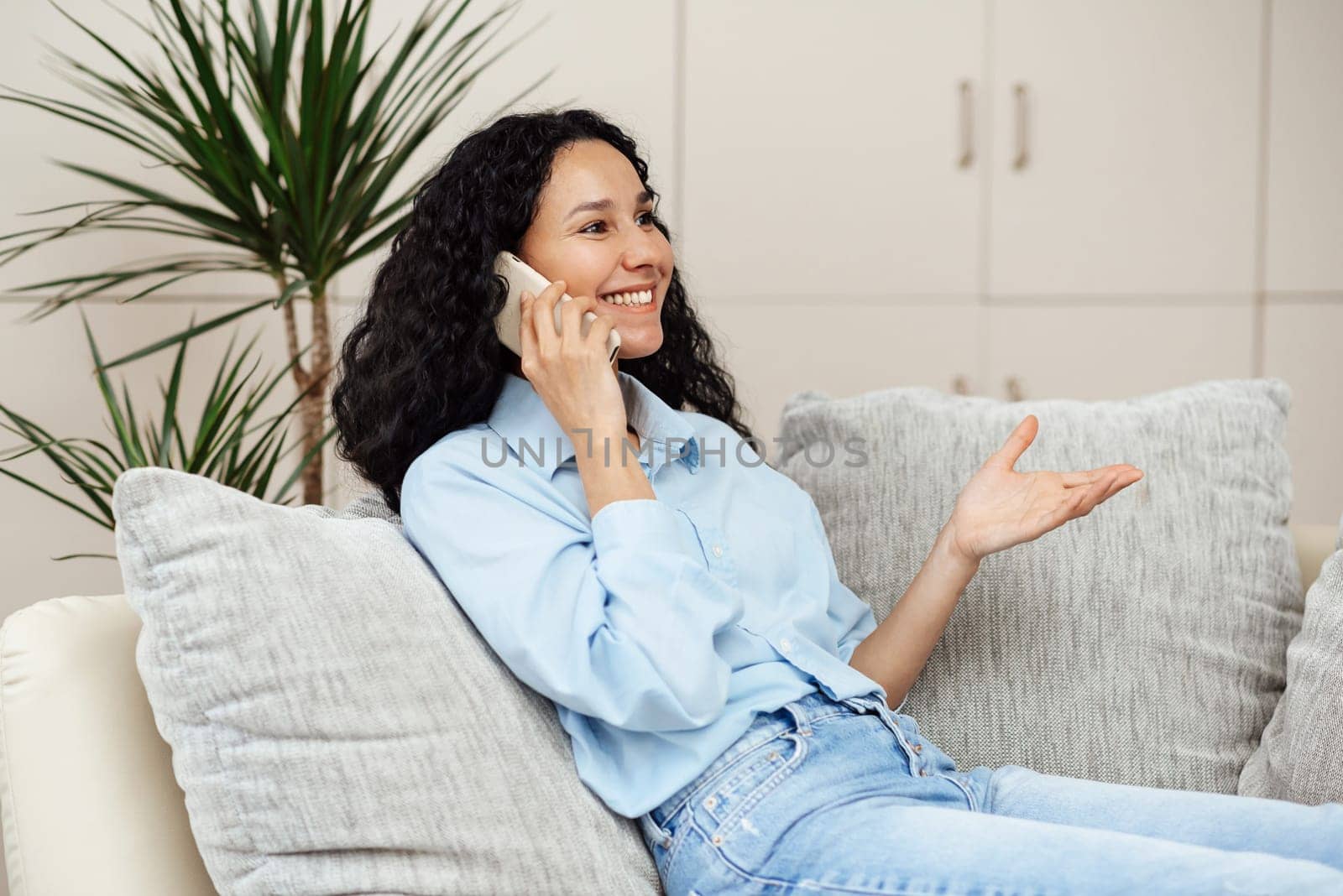 Beautiful young woman of Arab appearance and talking on the phone Sitting on the sofa smiling . The girl has a pleasant conversation and enjoys communication.