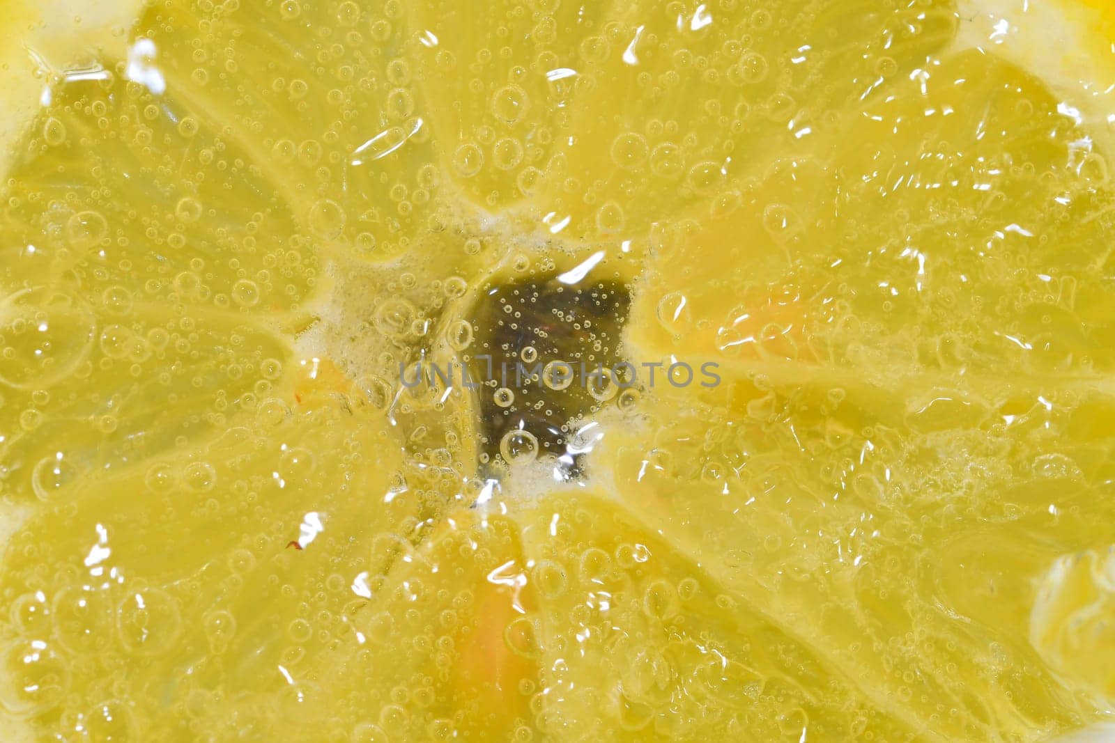 Slice of ripe lemon in water on white background. Close-up of lemon in liquid with bubbles. Slice of ripe citron in sparkling water. Macro image of fruit in carbonated water. by roman_nerud
