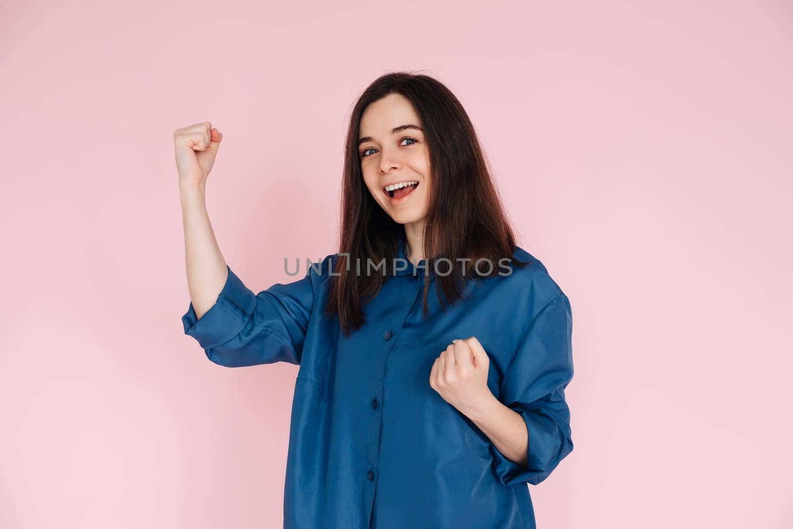Triumphant Celebration: Photo of an Ecstatic Lady Raising Fists in Joyful Achievement, Embracing Success in an Empty Space, Isolated on a Vibrant Pink Background.