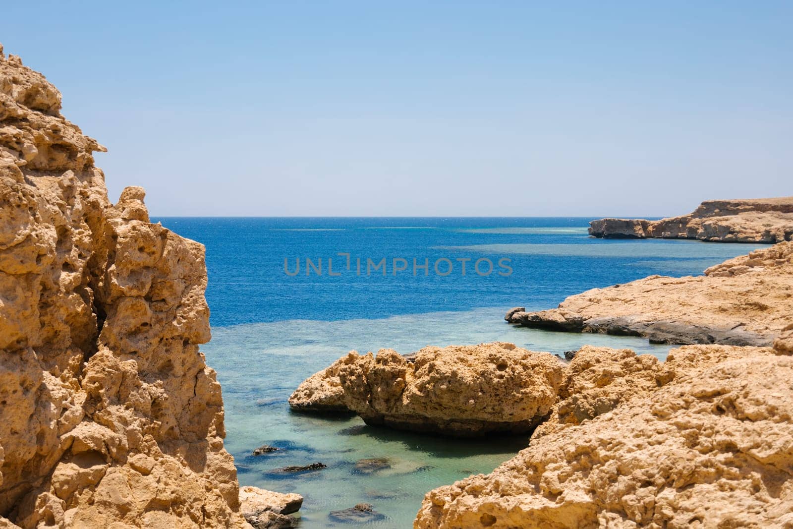 Sandy and rocky coast with blue color of water. Desolate beach on the coast shore of Red Sea. Ras Muhammad in Egypt at the southern extreme of the Sinai Peninsula. Travel concept.