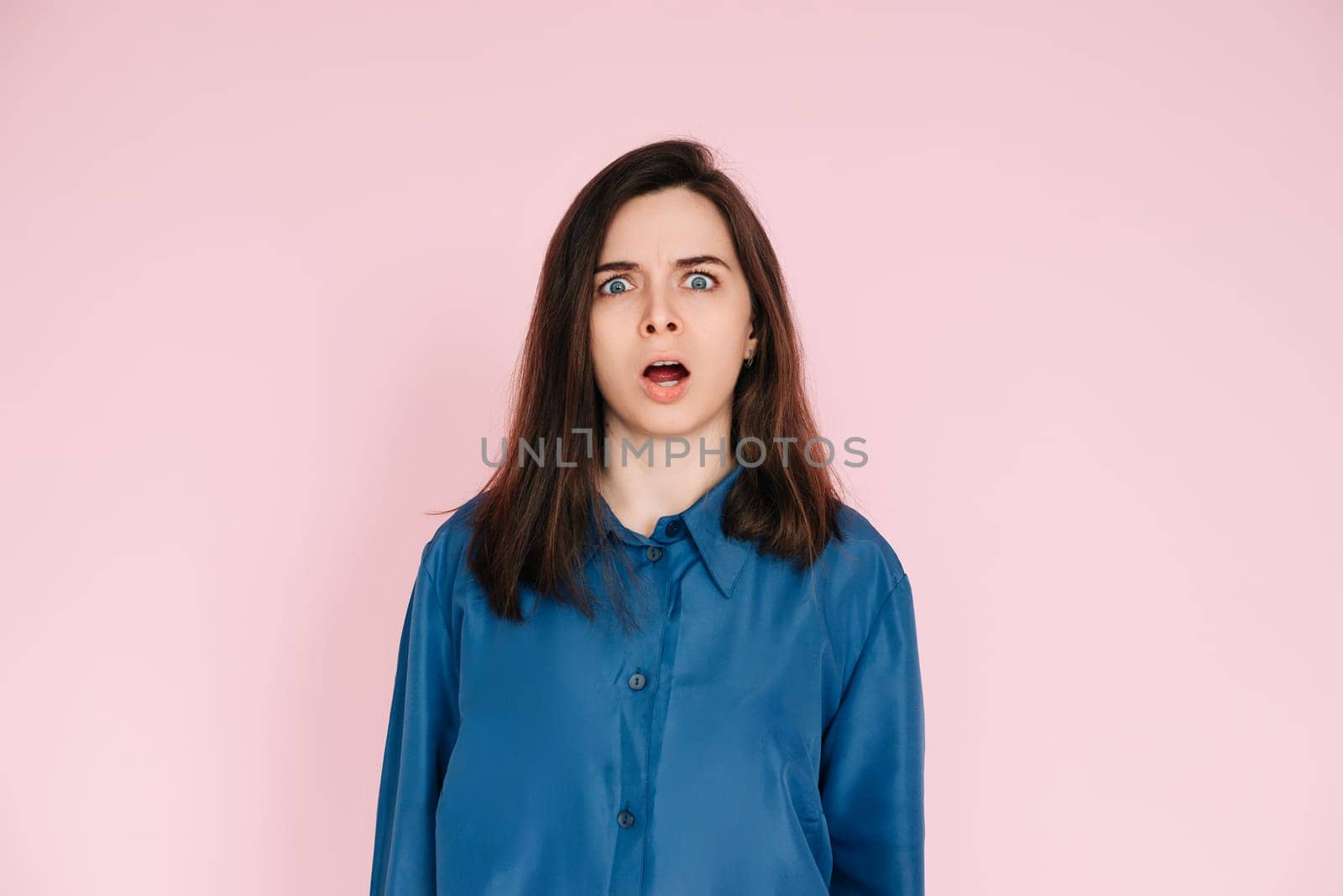 Stunning Portrait of a Speechless Woman in Utter Shock, Wide Open Mouth, Expressing Unbelievable Surprise - Isolated on Vibrant Pink Background.