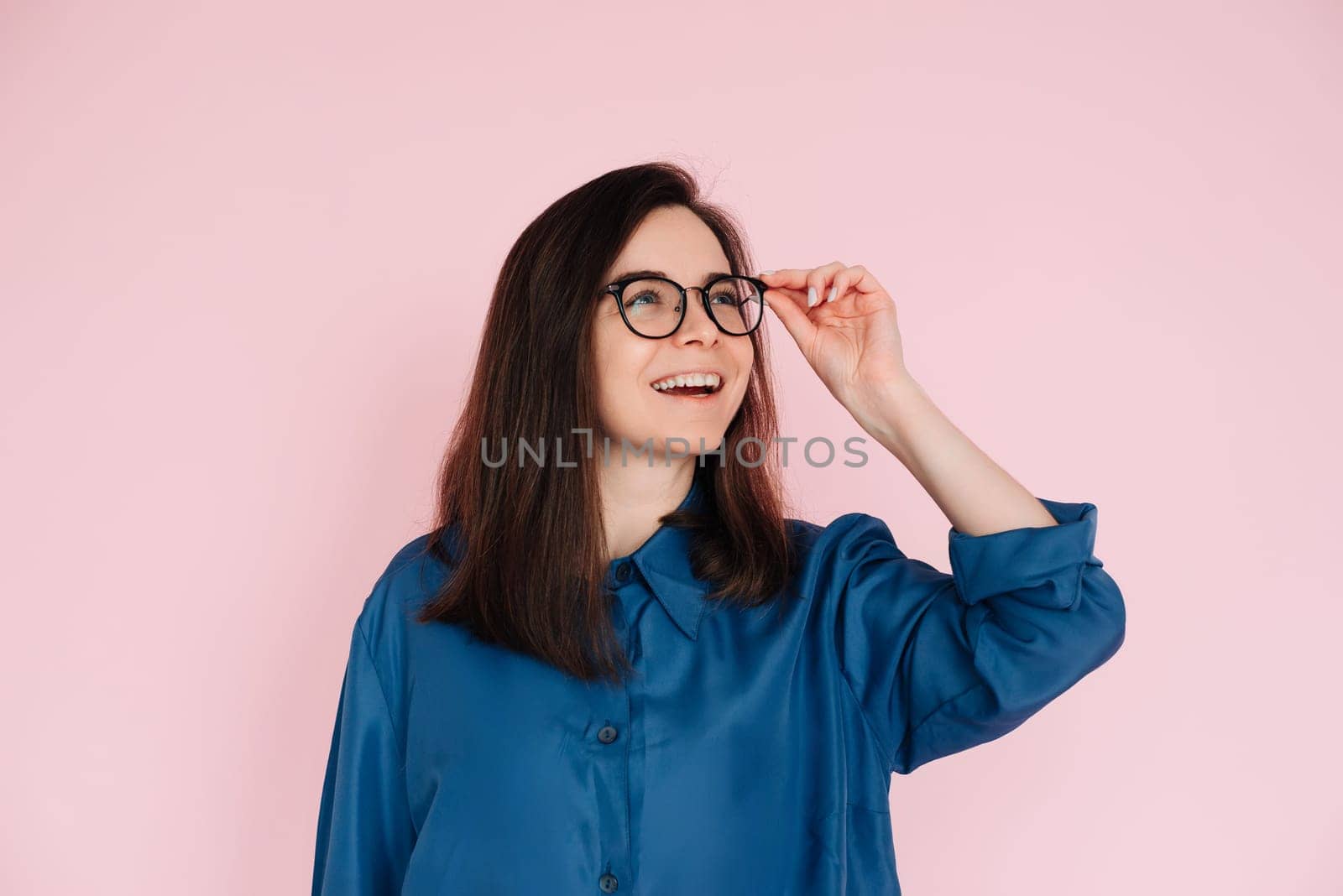 Curious Woman Touching Glasses, Deep in Thought, Searching for Inspiration in Empty Space: Isolated Pink Background Portrait.