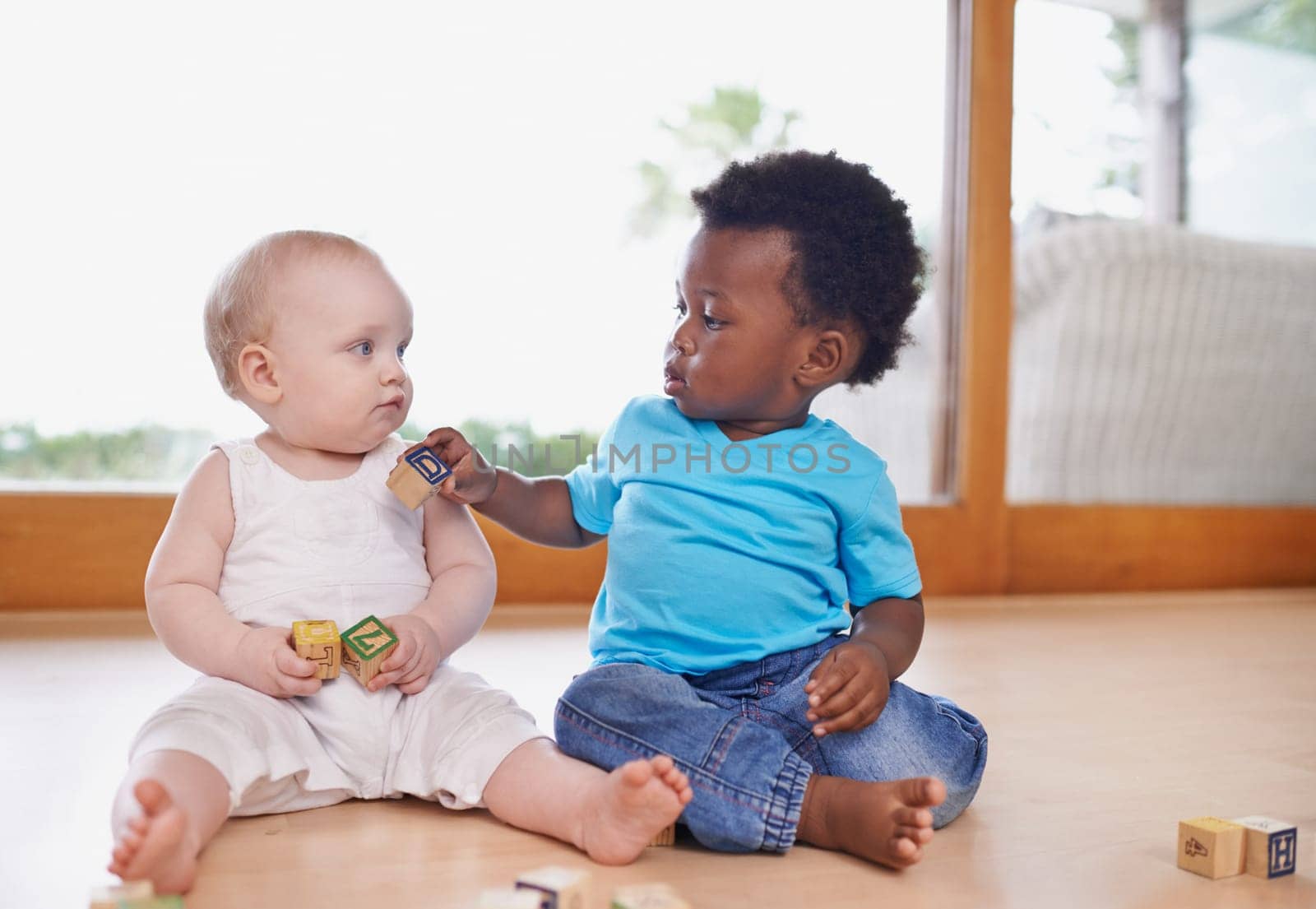 Baby, friends and building blocks on a floor while bonding, learning and playing in daycare, calm and sweet. Kids, diversity and puzzle toy for curious babies having fun with child development game.