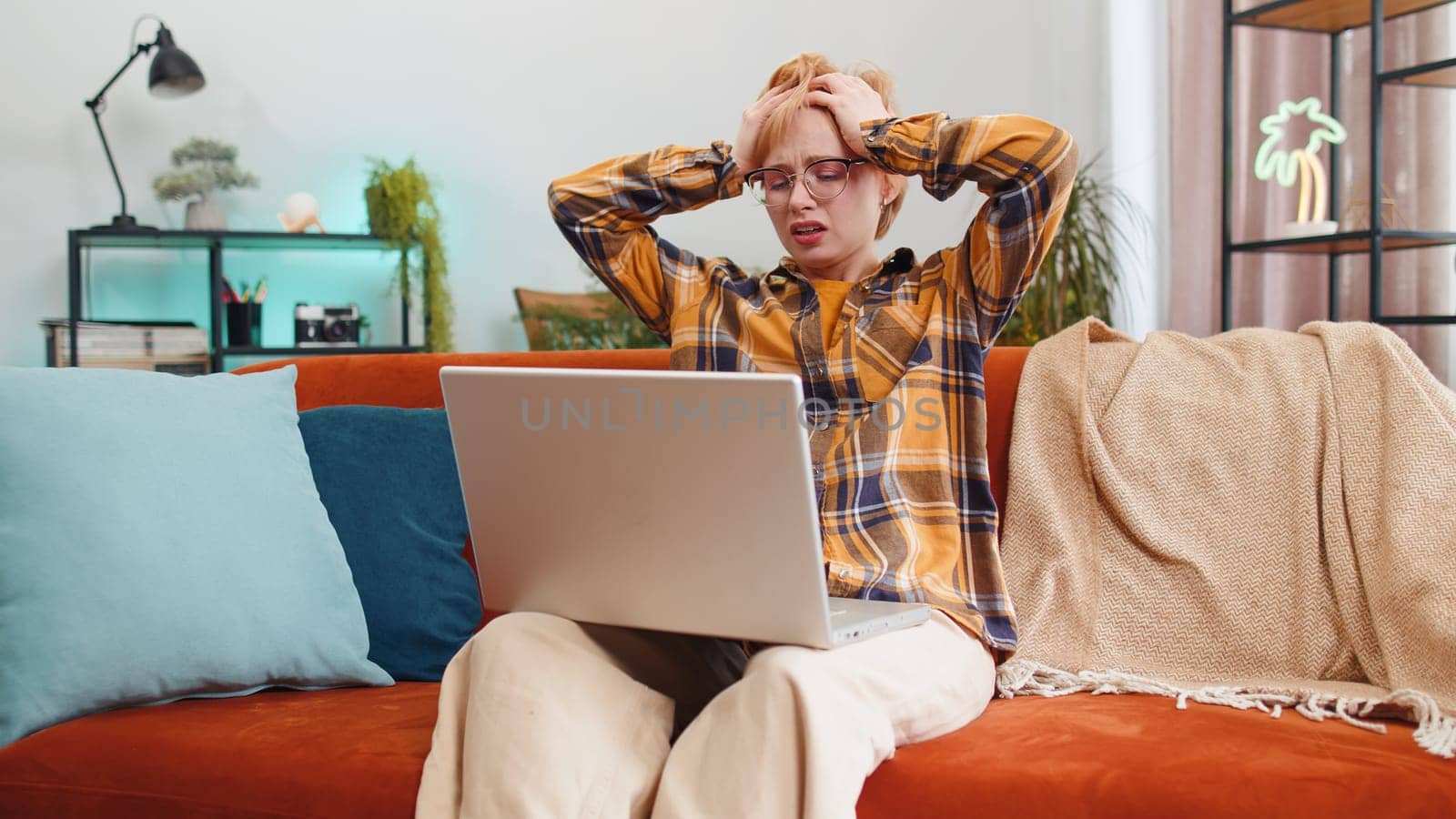 Displeased woman use laptop notebook typing browsing working, loses becoming surprised sudden lottery results bad news fortune loss fail computer virus. Portrait of girl at home in room on couch