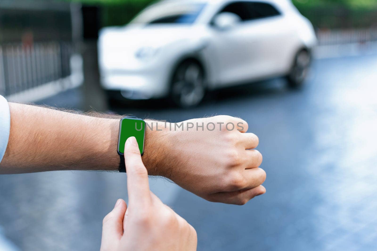 Focus mockup smartwatch with green screen for hologram or interface copyspace of electric car battery that recharging at charging station. Progressive mockup device mockup with green screen.