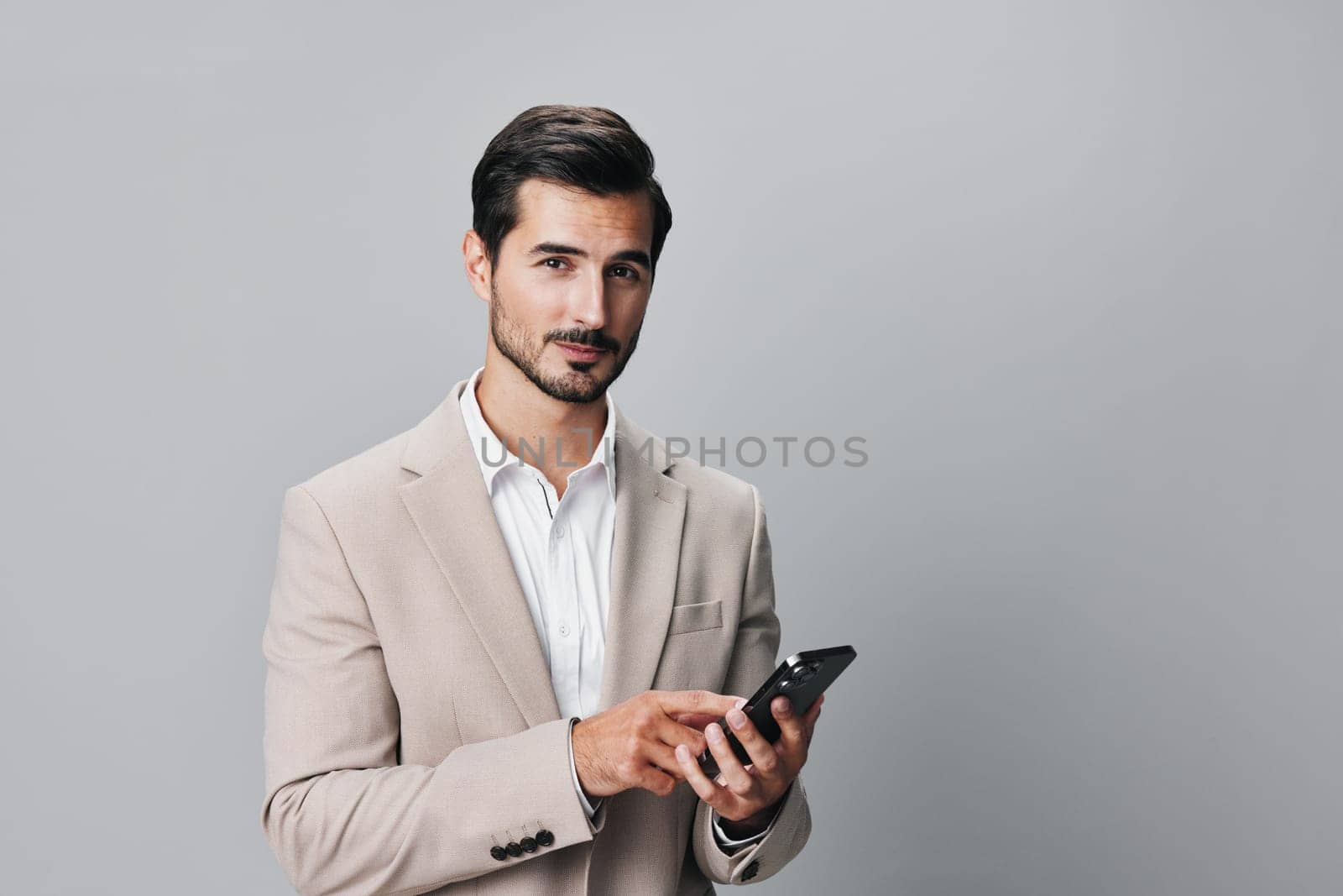 hold man cyberspace copy space beige connection gray male entrepreneur smile business technology white holding call suit smartphone young phone happy portrait