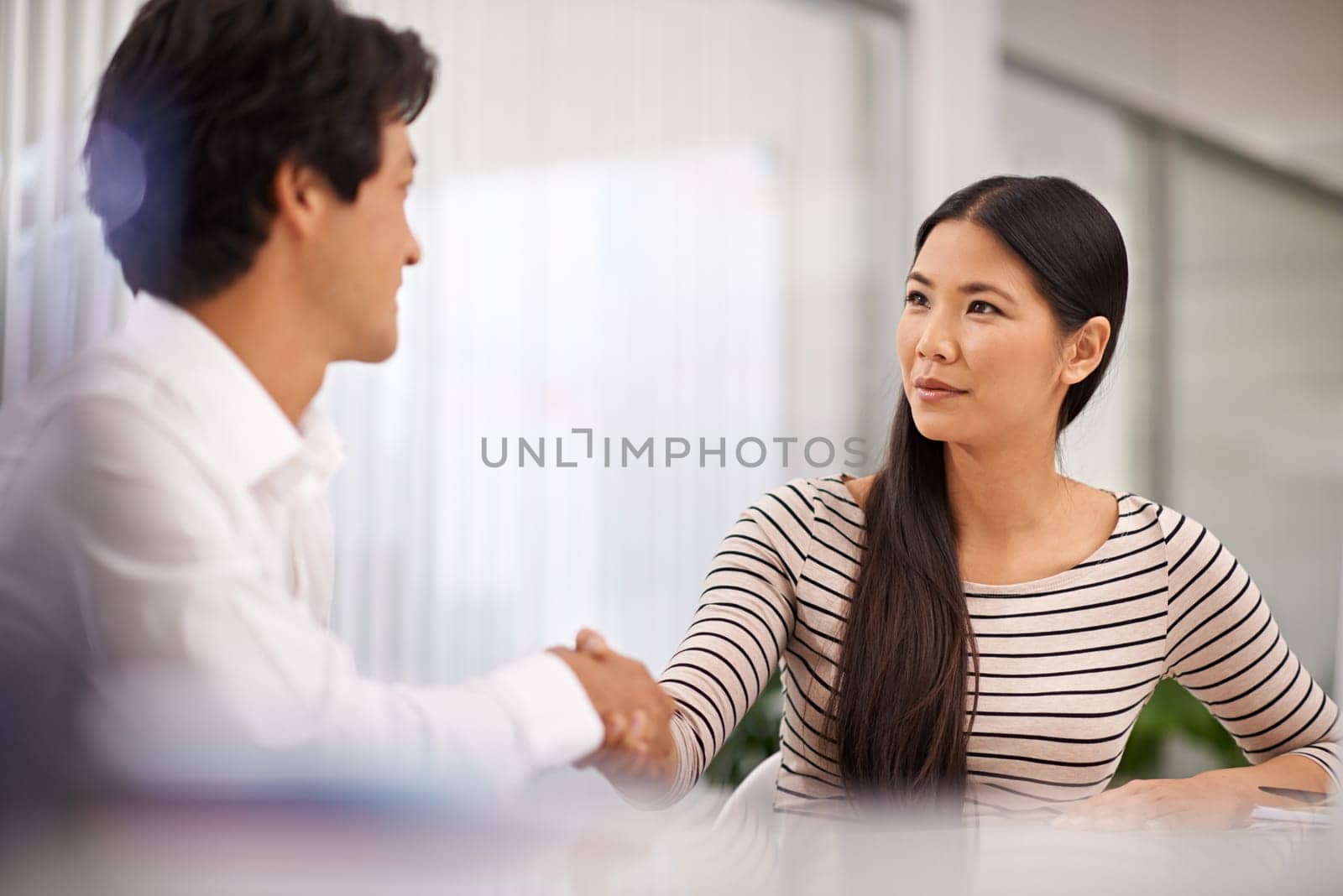 I think that went really well. two businesspeople shaking hands while seated in an office