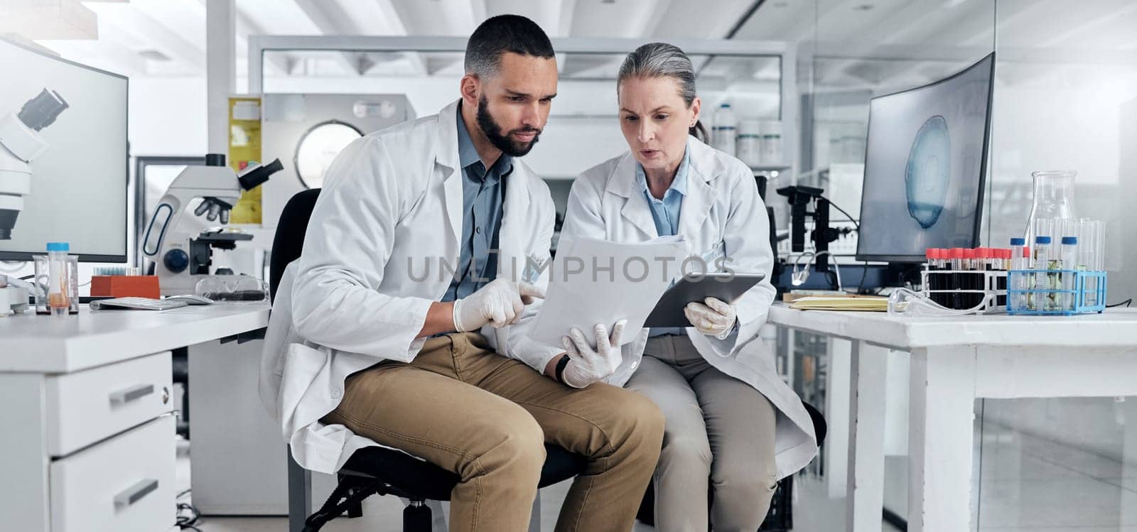 Scientist partnership document for medical research laboratory discussion in healthcare science future innovation report. Man and woman doctor teamwork talk on exam or test analysis biology paperwork by YuriArcurs