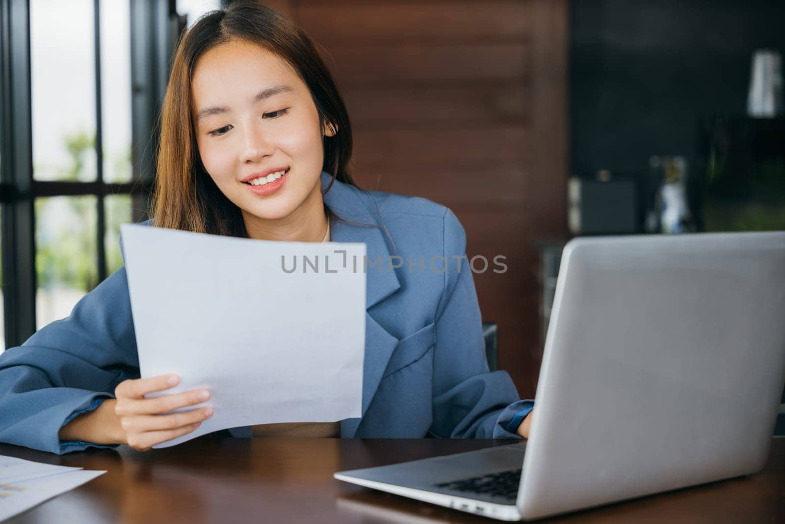 Asian smiling young business woman reading report document compare with laptop computer, Happy accounting female reviewing data in financial charts and graphs outside at cafe coffee shop