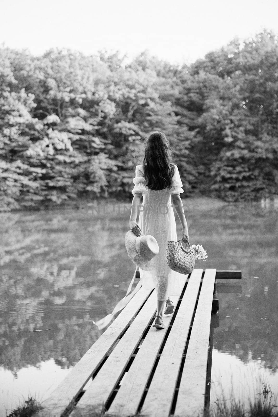 monochrome photo of a woman resting on a lake in the countryside in a long summer dress by Vichizh