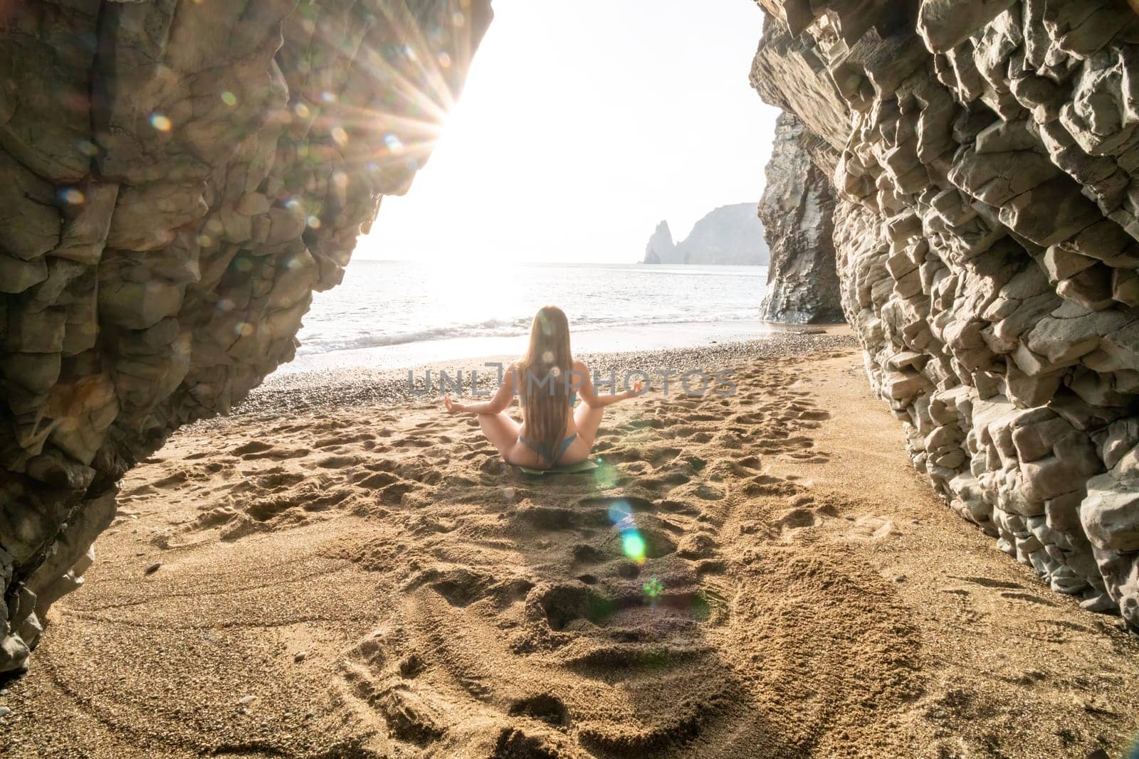 Middle aged well looking woman with black hair doing Pilates with the ring on the yoga mat near the sea on the pebble beach. Female fitness yoga concept. Healthy lifestyle, harmony and meditation.