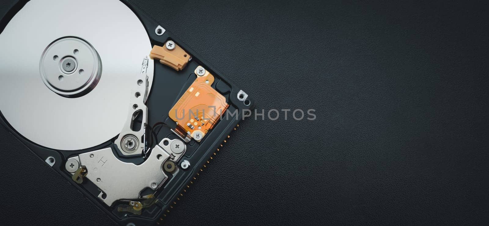 Disassembled open hard disk drive HDD of computer or laptop lies on dark matte surface. Сomputer hardware and equipment. Harddisk data storage. by Unimages2527