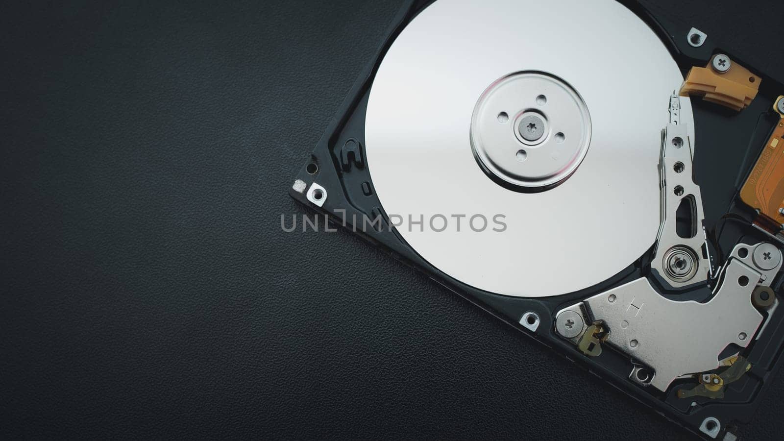 Disassembled open hard disk drive HDD of computer or laptop lies on dark matte surface. Сomputer hardware and equipment. Harddisk data storage.