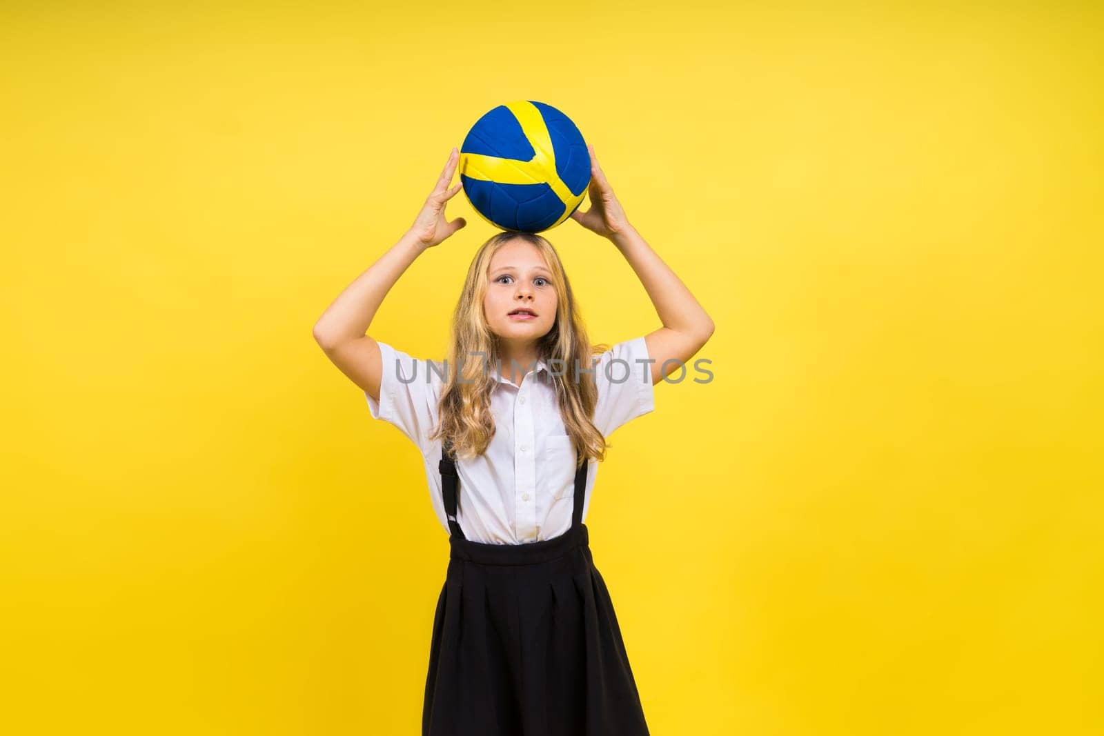 Portrait of cute eight year old girl in volleyball outfit isolated on a red yellow background