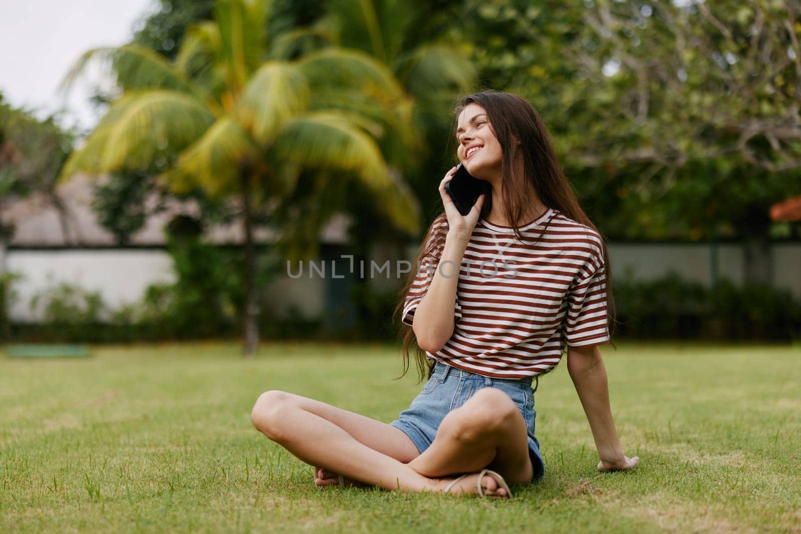 healthy woman smart girl cell tree nature happy working park blogger grass smiling lifestyle phone smartphone walk app female palm jeans spring