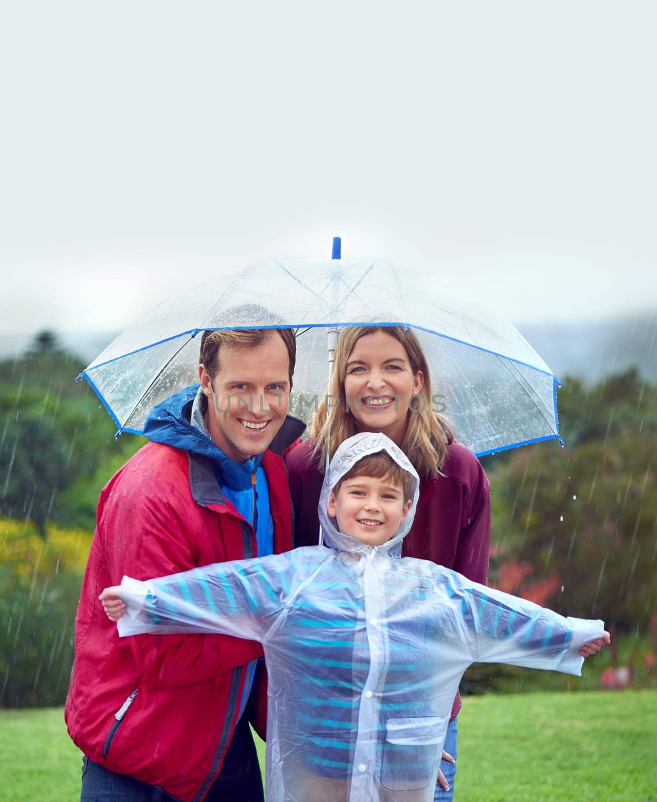 Portrait, family and happy portrait in rain with umbrella outdoor in nature for fun, happiness and quality time. Man, woman and excited child together for water drops, playing and freedom with mockup.