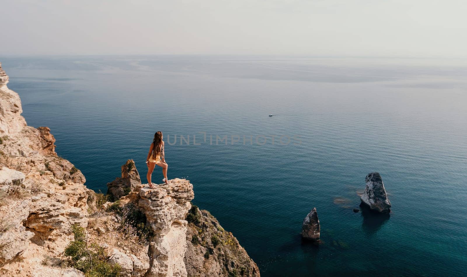 Woman travel sea. Happy tourist taking picture outdoors for memories. Woman traveler looks at the edge of the cliff on the sea bay of mountains, sharing travel adventure journey.