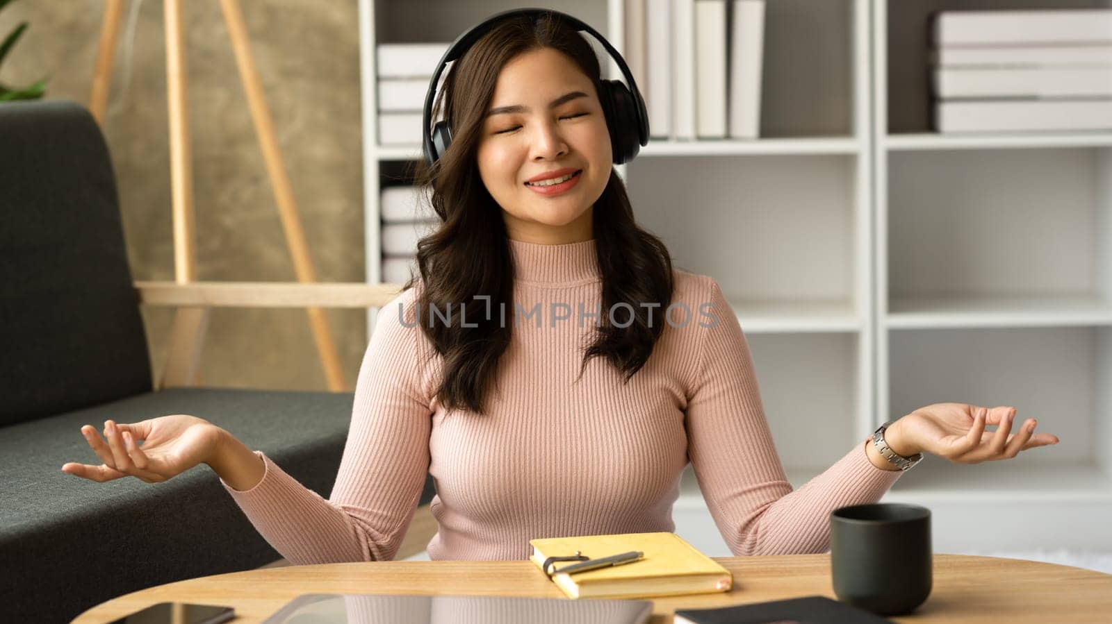 Tranquil asian woman listening favorite song in headphones, enjoying peaceful weekend time at home.